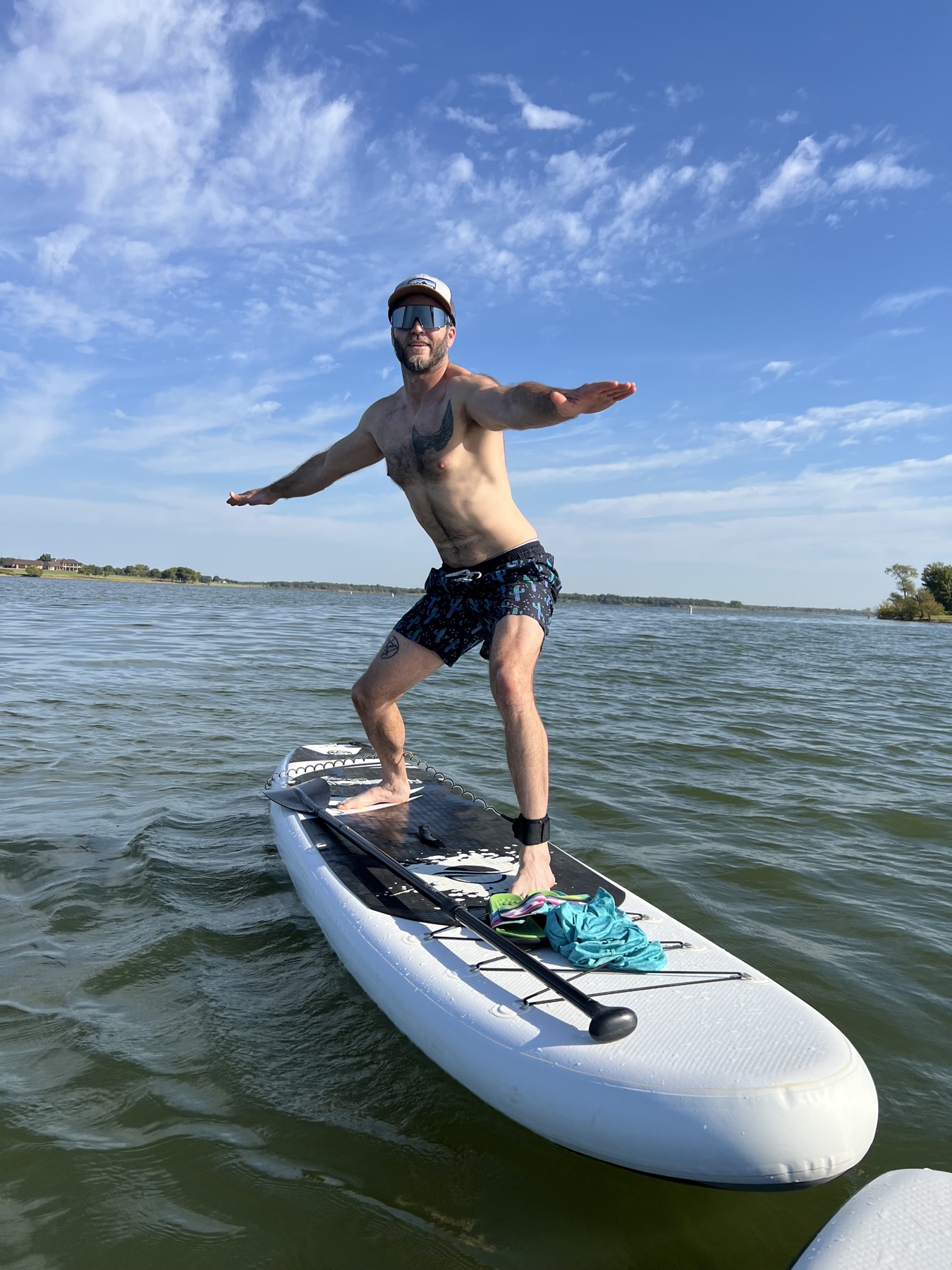 Jeff balancing on a paddleboard on a sunny lake